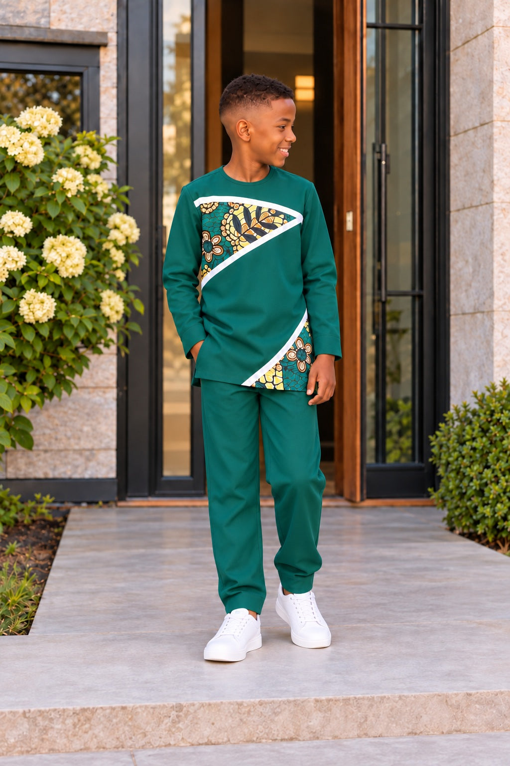 Garçon portant l’ensemble URIALEX vert émeraude, tunique à motifs dorés et pantalon de coupe confortable avec baskets blanches.