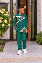 Garçon portant l’ensemble URIALEX vert émeraude, tunique à motifs dorés et pantalon de coupe confortable avec baskets blanches.